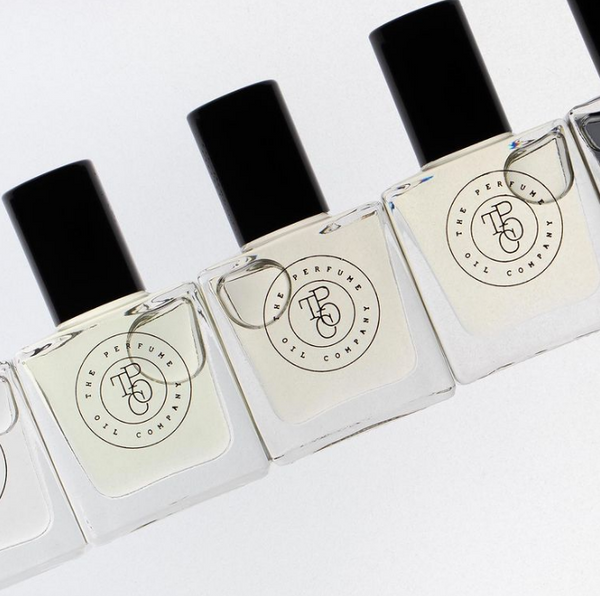 A row of square perfume oil roll-on bottles with black caps, angled view