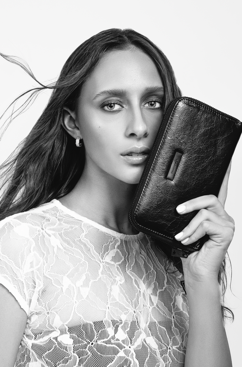 Model holding the black Minky leather wallet up beside her face