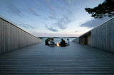 A group of people sitting on a wooden deck at dusk, creating a Rock the Shack Books refuge.