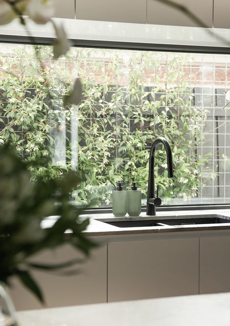 Kitchen benchtop with Smith & Co. bottles and garden greenery through the window