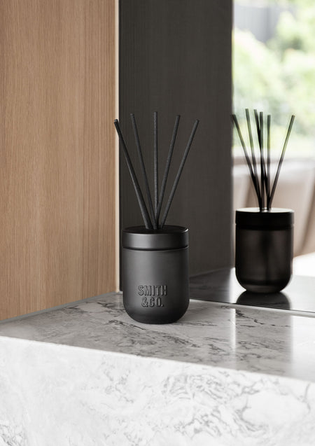 Two Smith & Co. diffusers on a marble ledge against timber panelling