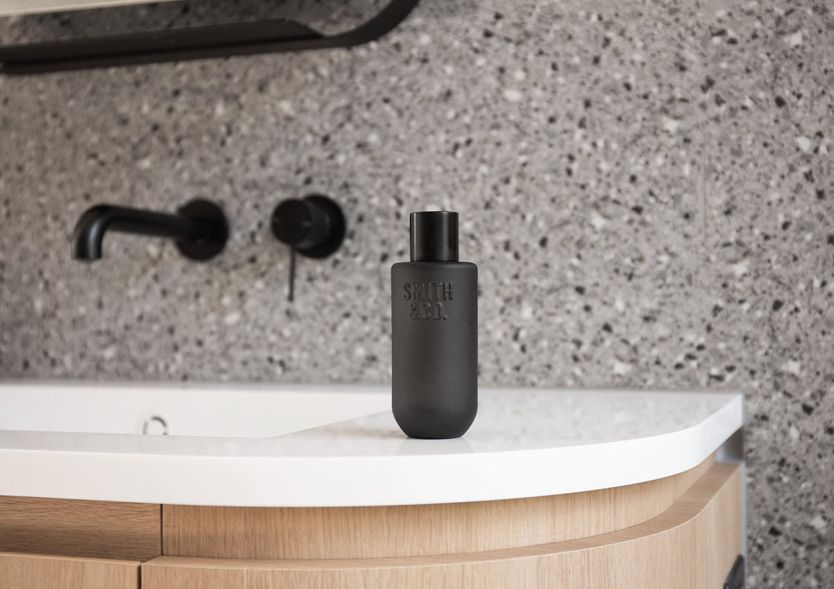 Black Smith and Co room spray on a white basin vanity against terrazzo