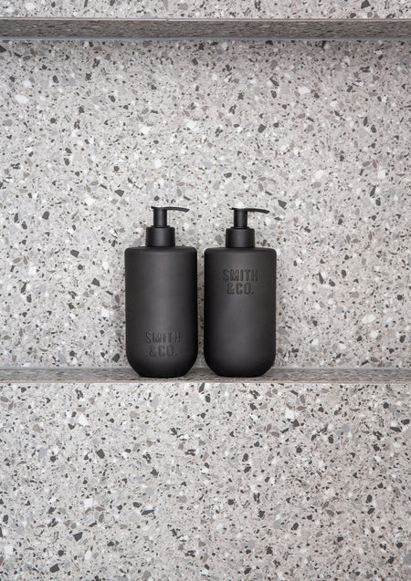 Two Smith & Co. bottles on a terrazzo shower shelf