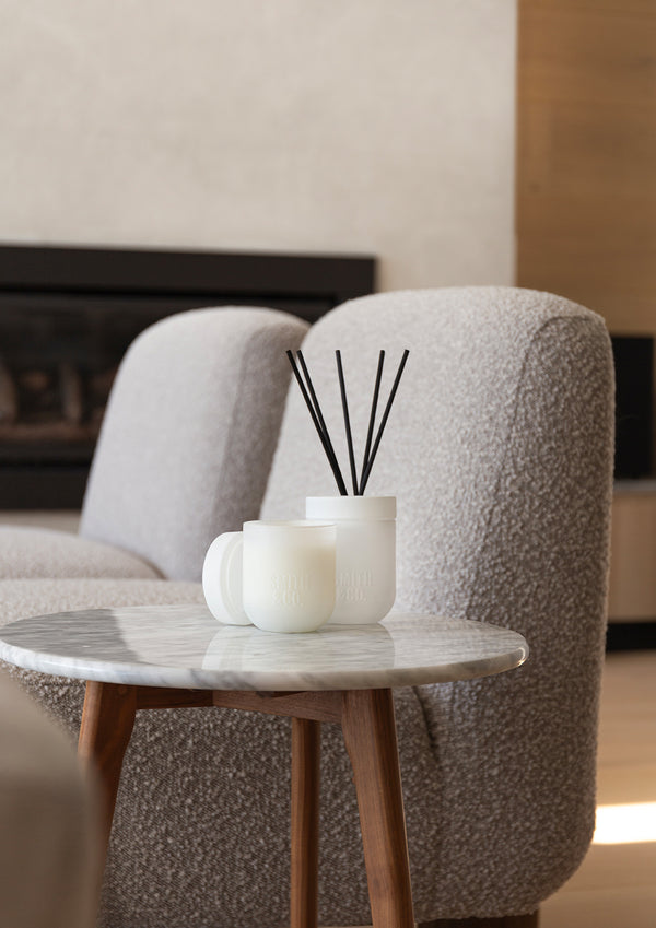 White Smith and Co diffuser and a candle on a marble side table beside a boucle chair