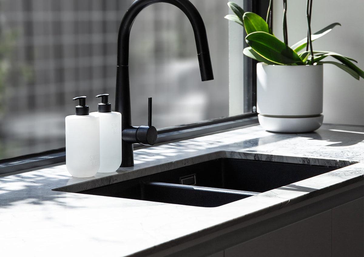 Smith and Co bottles at a white benchtop sink with a potted plant