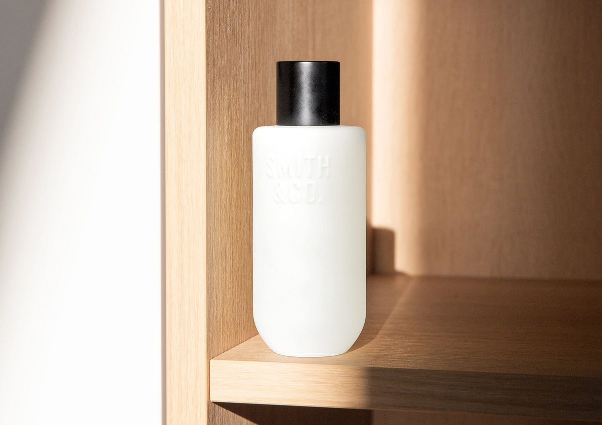 Wide view of the frosted room spray standing on a timber shelf in a sunlit niche