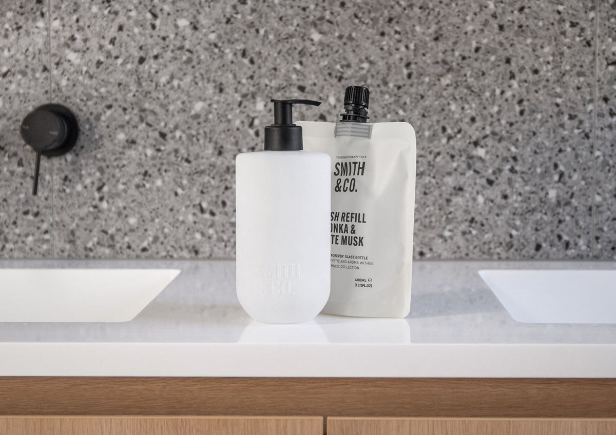 Smith & Co. Tonka & White Musk wash bottle and refill pouch on a white vanity with a terrazzo splashback