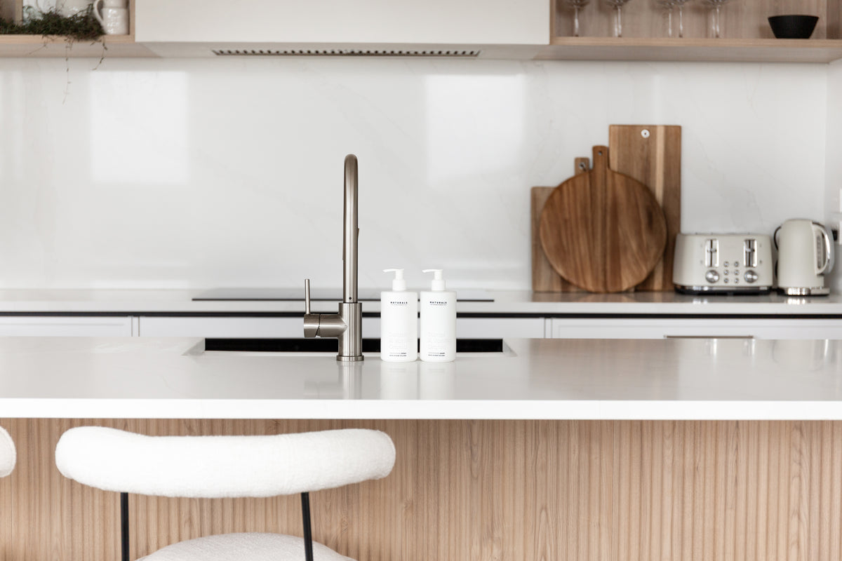 Kitchen bench with toaster and timber boards, Naturals bottles by the tap, fluted island below