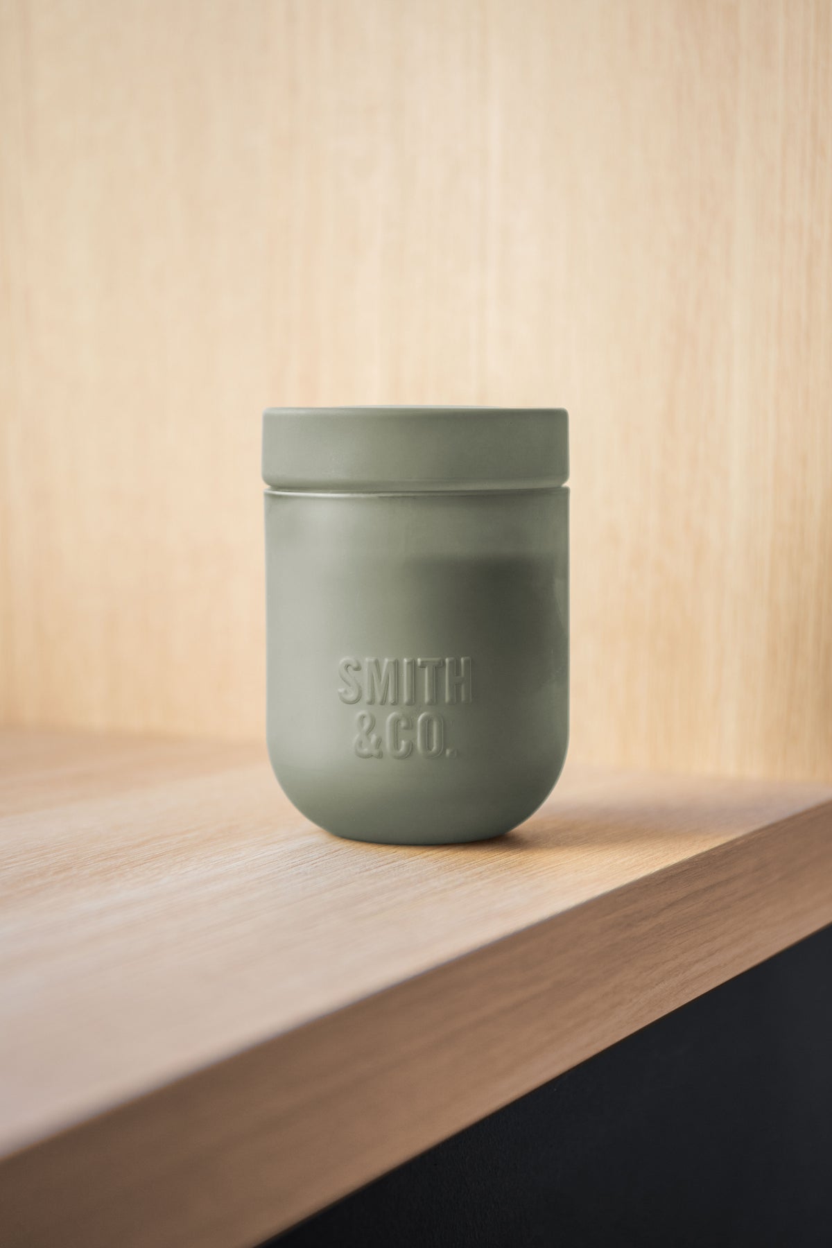 Smith and Co candle with its lid on, on the edge of a pale timber shelf