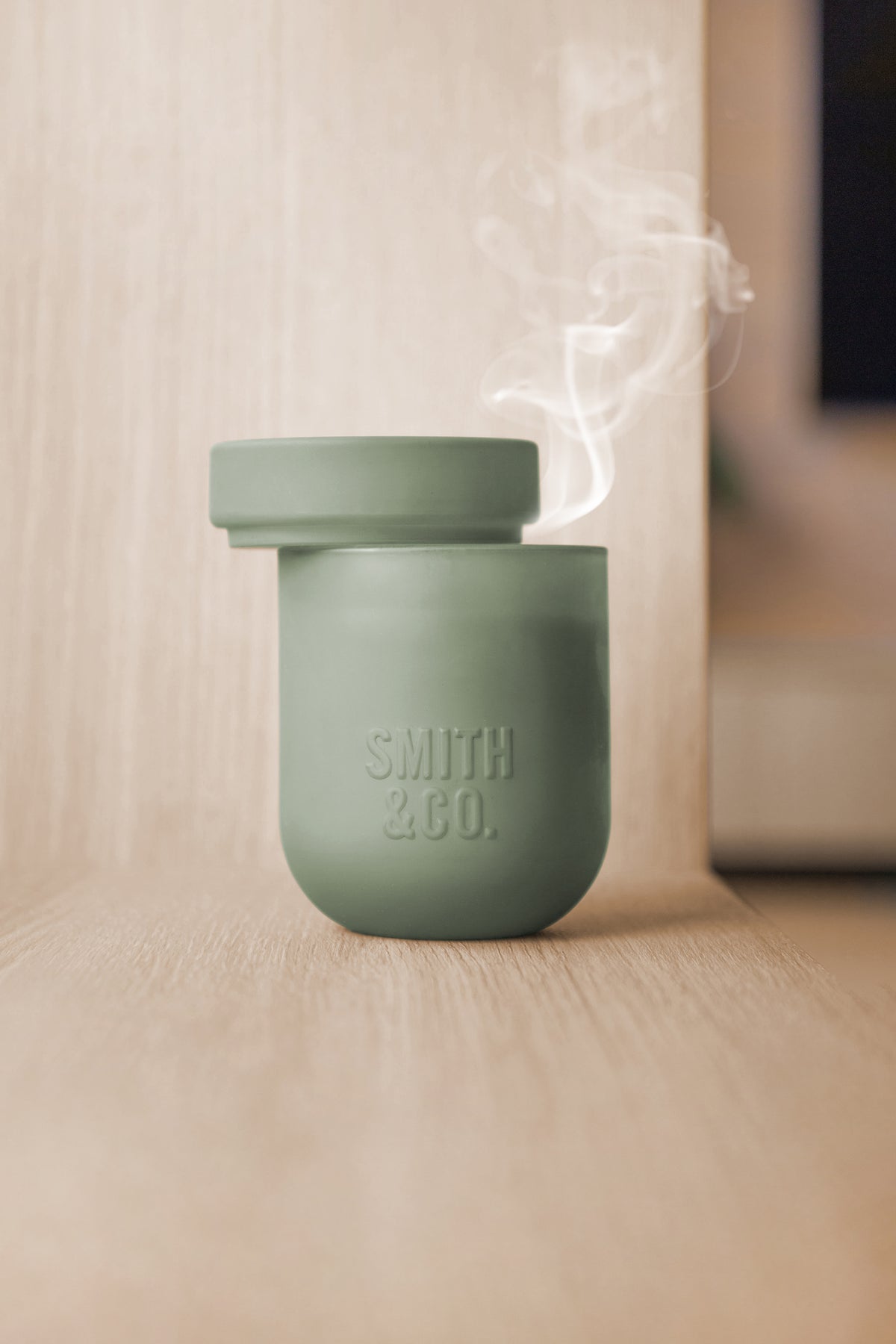 Lit Smith and Co candle on a stone bench in a bright open room