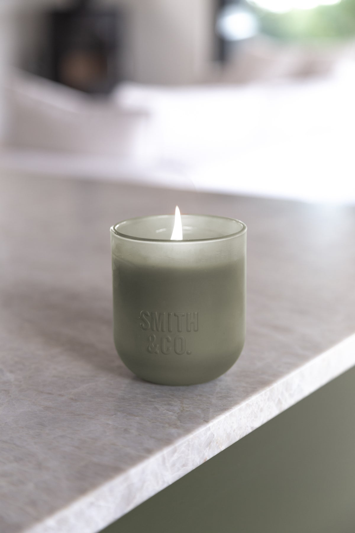 Lit Smith and Co candle on the corner of a dark timber sideboard