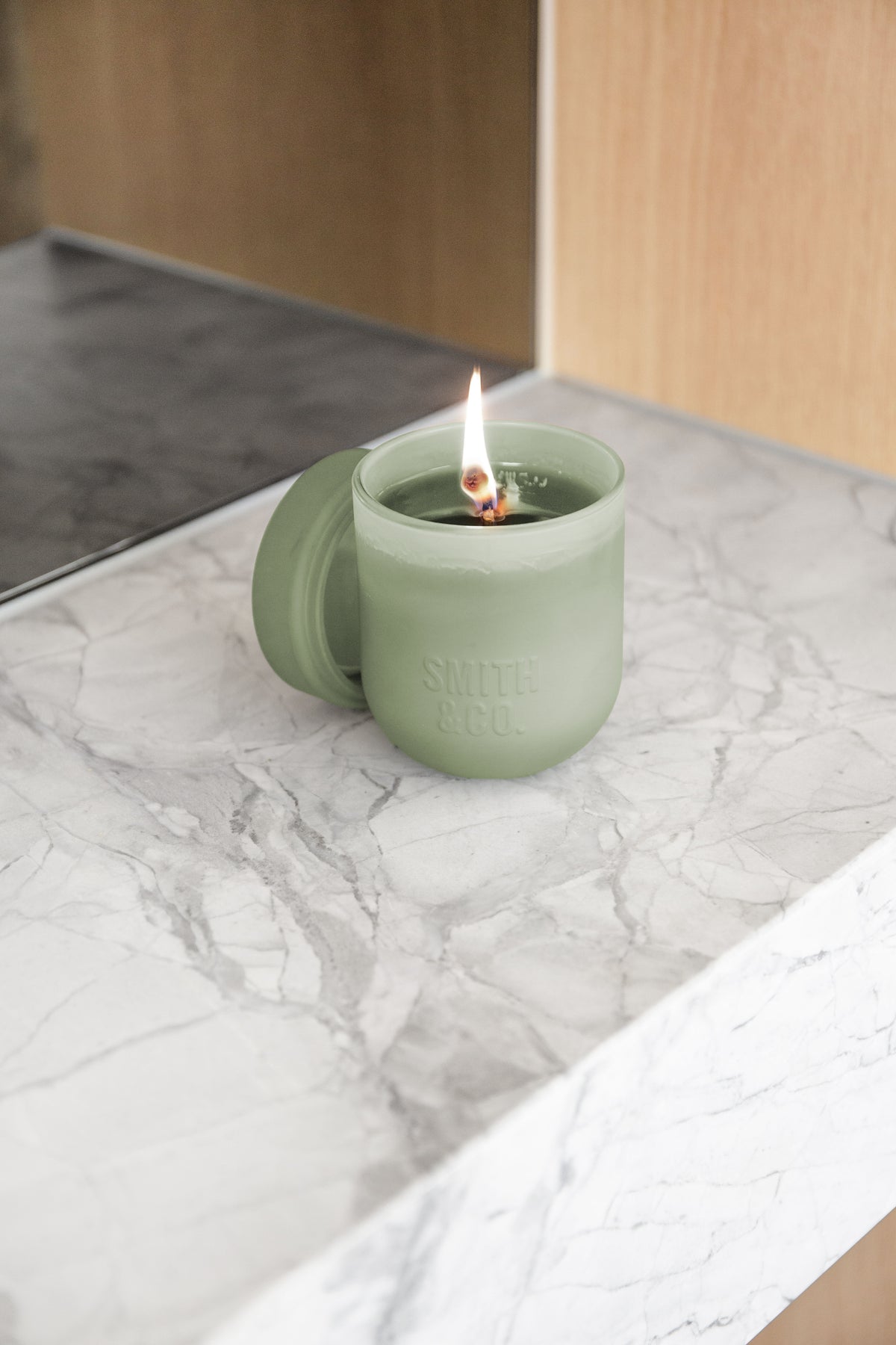 Lit Smith and Co candle on a marble ledge seen from above