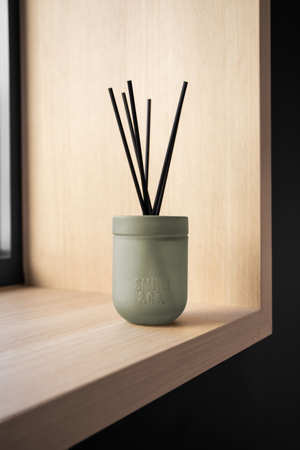 Smith and Co reed diffuser in a pale timber niche against a dark recess