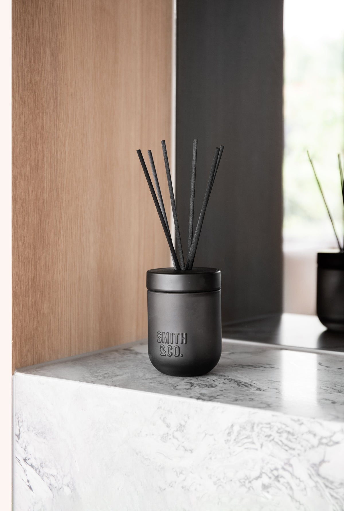 Smith & Co. diffuser on a marble ledge beside timber panelling and a black wall