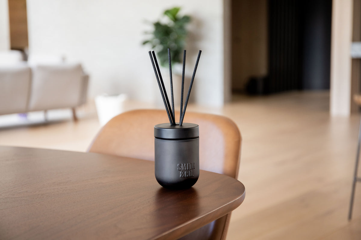 Smith & Co. diffuser on a timber table with a potted plant in the living area behind