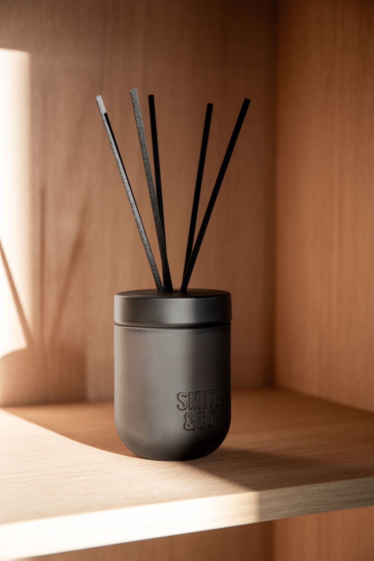 Smith & Co. diffuser on a timber shelf in warm, low light