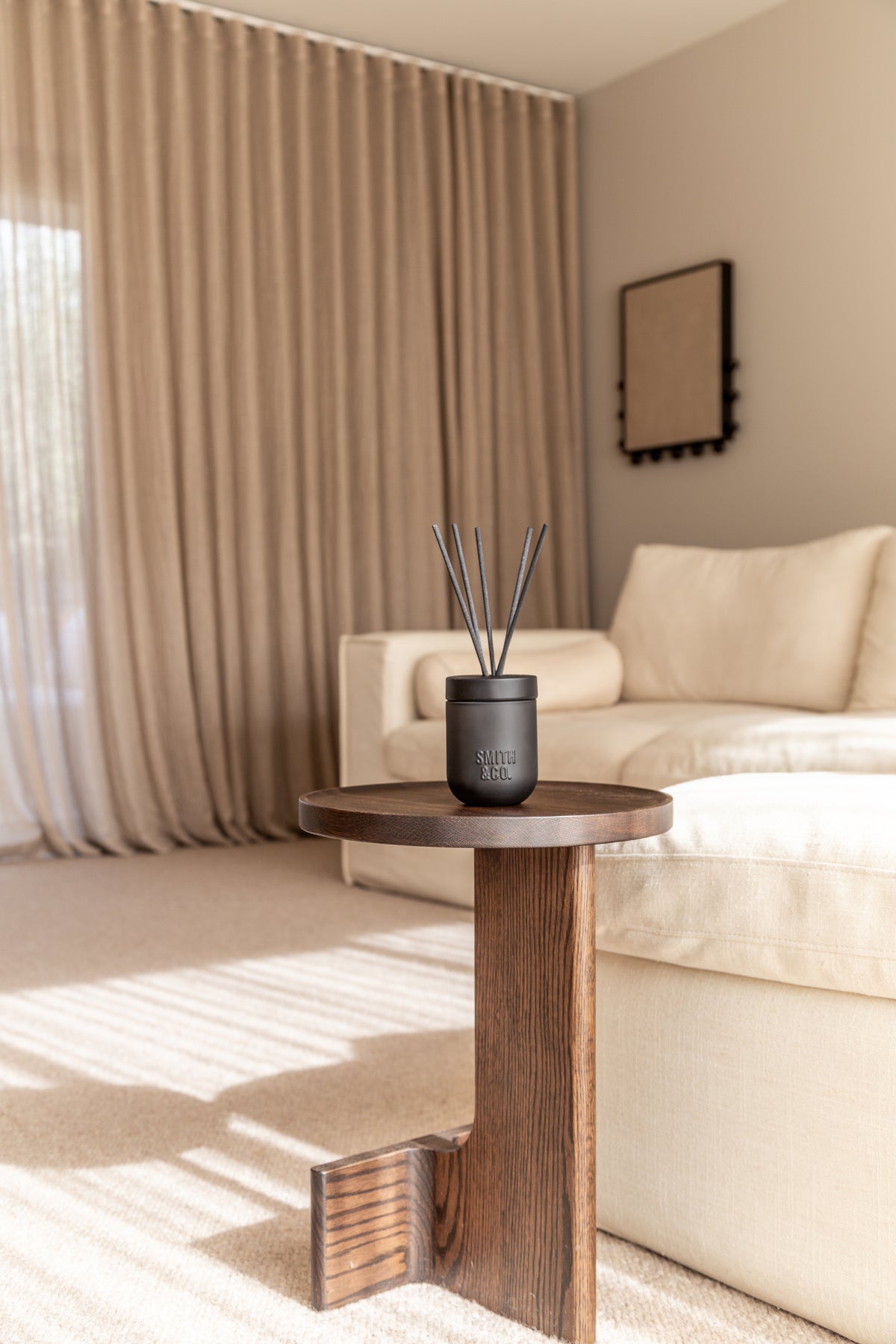 Living room with a cream sofa and sheer curtains, Smith & Co. diffuser on a side table
