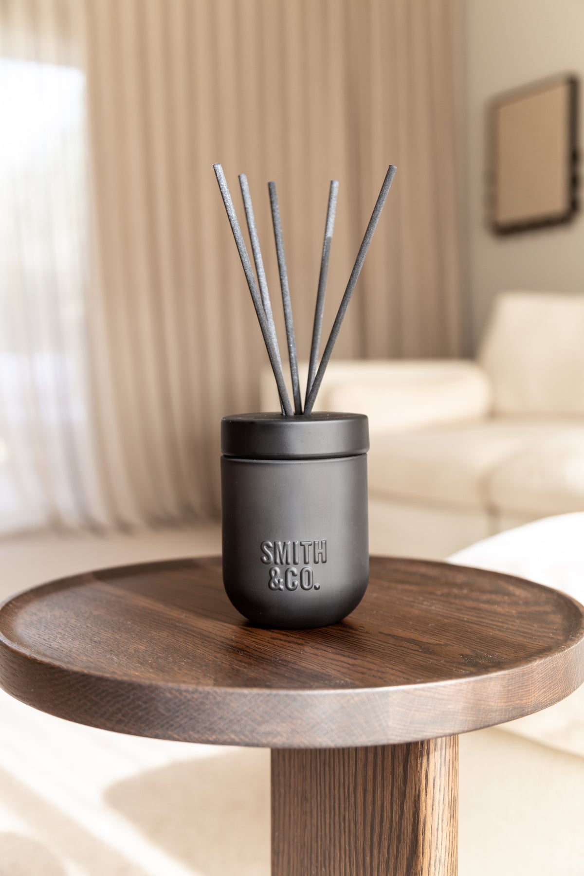 Smith & Co. diffuser on a round timber table with sheer curtains behind