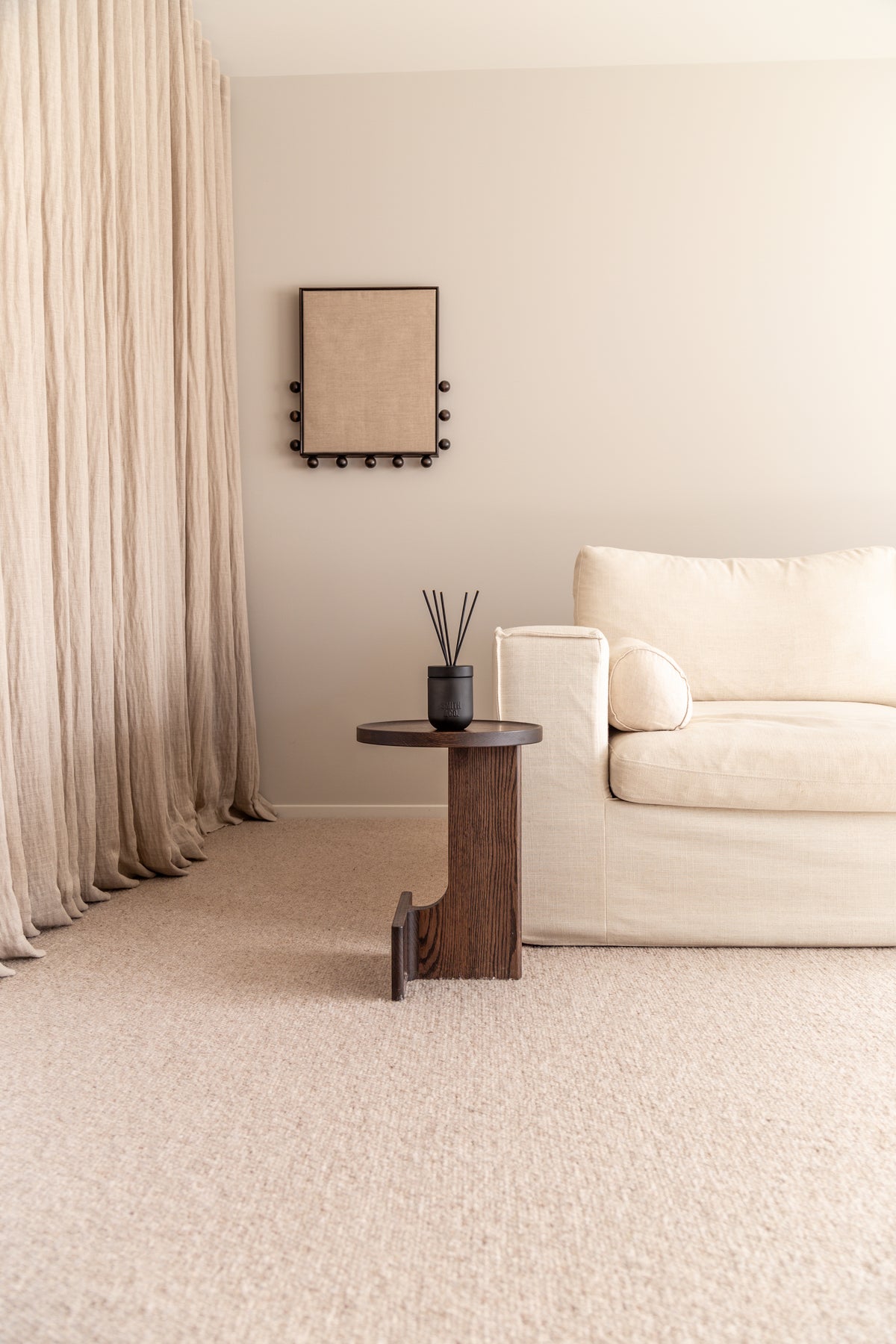 Pale living room with a timber side table holding the Smith & Co. diffuser