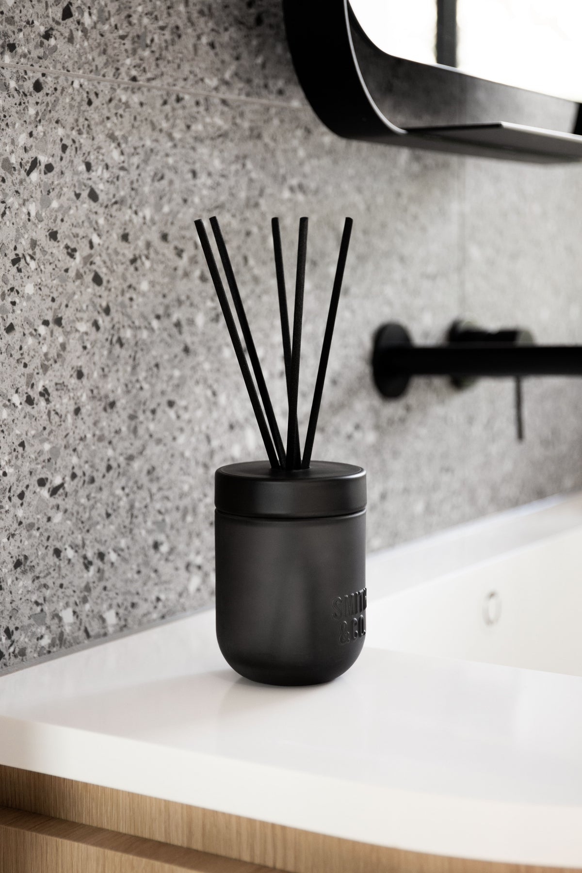 Smith & Co. diffuser beside a white basin and black tap against terrazzo