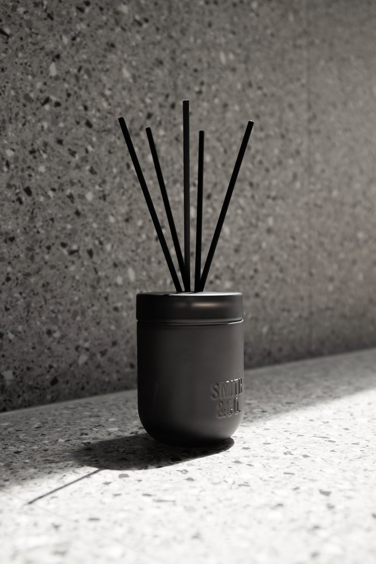 Smith & Co. diffuser against a speckled terrazzo wall with strong shadows