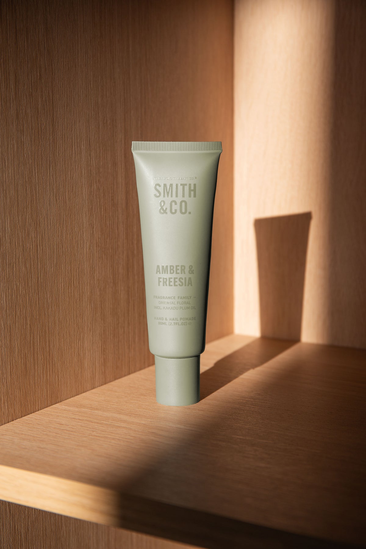 Hand cream tube on an oak shelf with a strong shadow cast on the panelling behind