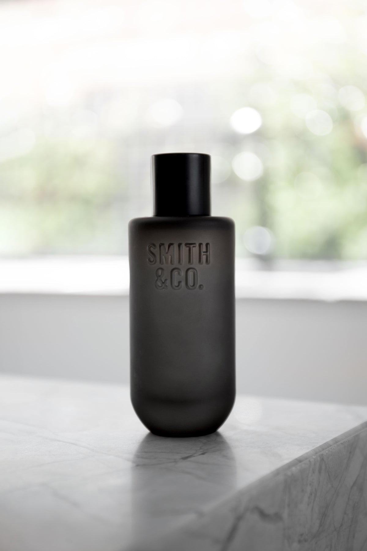 Black Smith and Co room spray on a marble ledge with a bright window behind