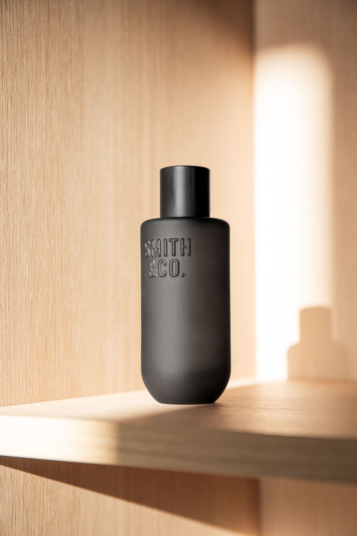 Black Smith and Co room spray on a timber shelf beside a glowing light strip