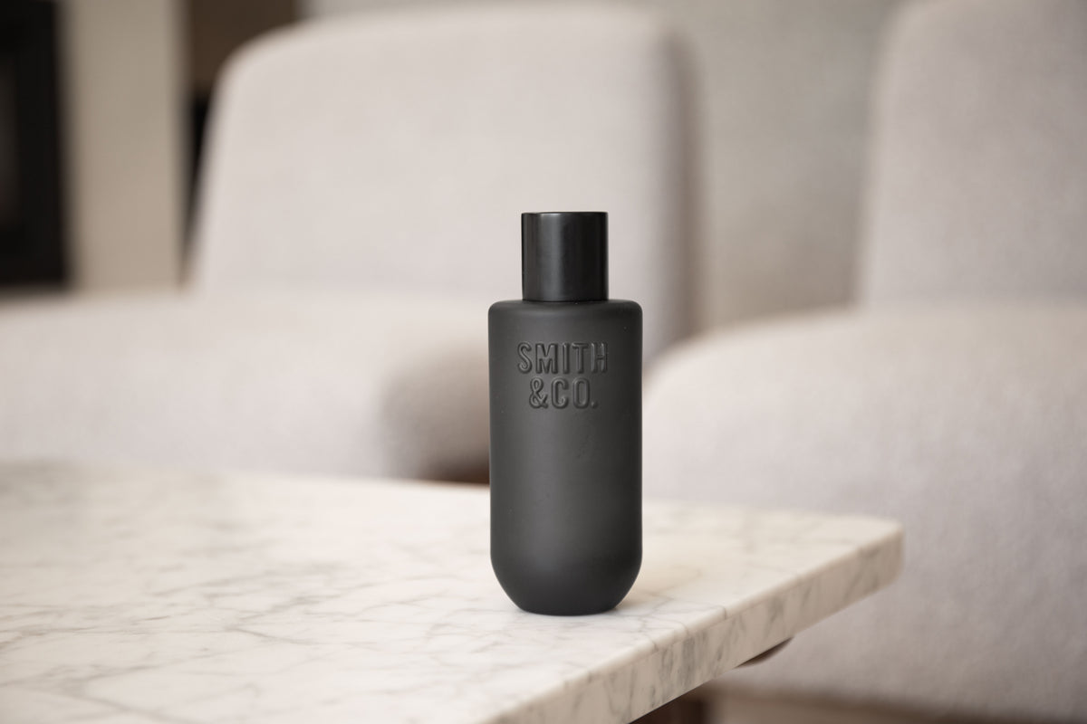 Wide view of the black Smith and Co room spray on a marble bench by boucle chairs