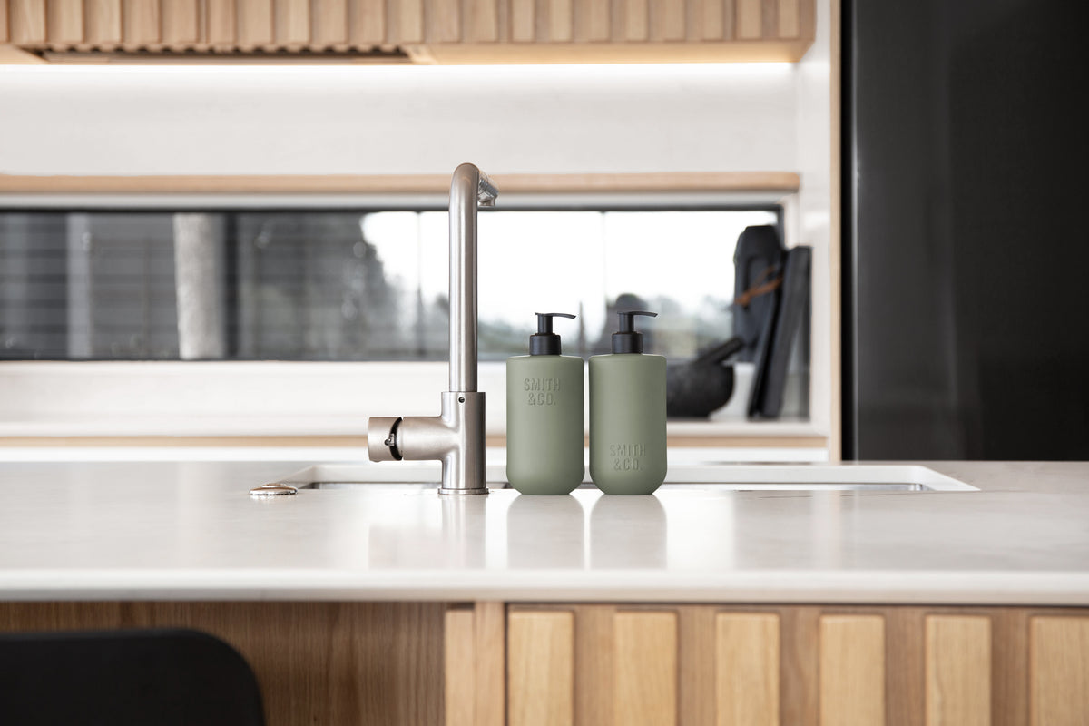 Kitchen with timber cabinetry and a white benchtop, Smith & Co. bottles by the sink