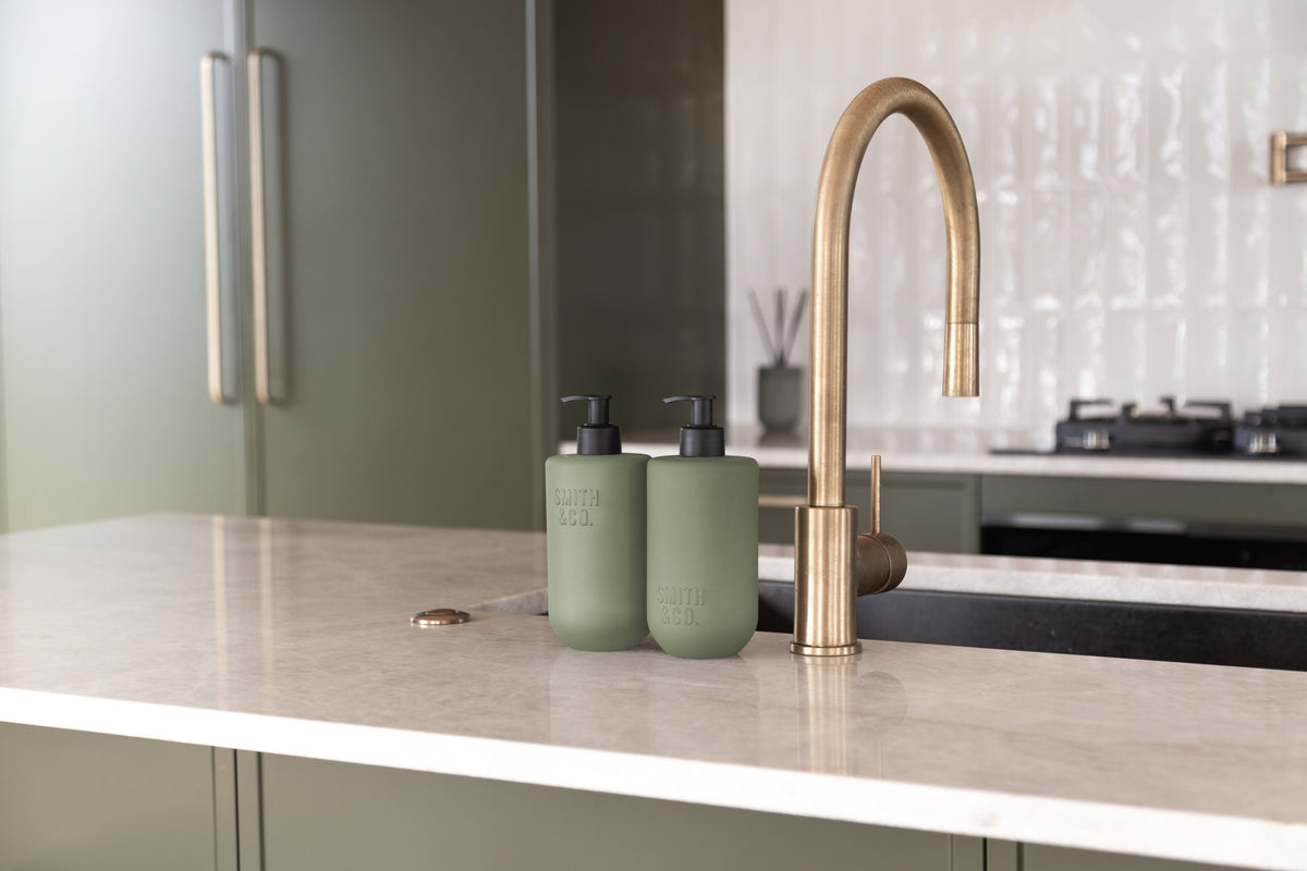 Kitchen with a brass gooseneck tap and Smith & Co. bottles by the sink