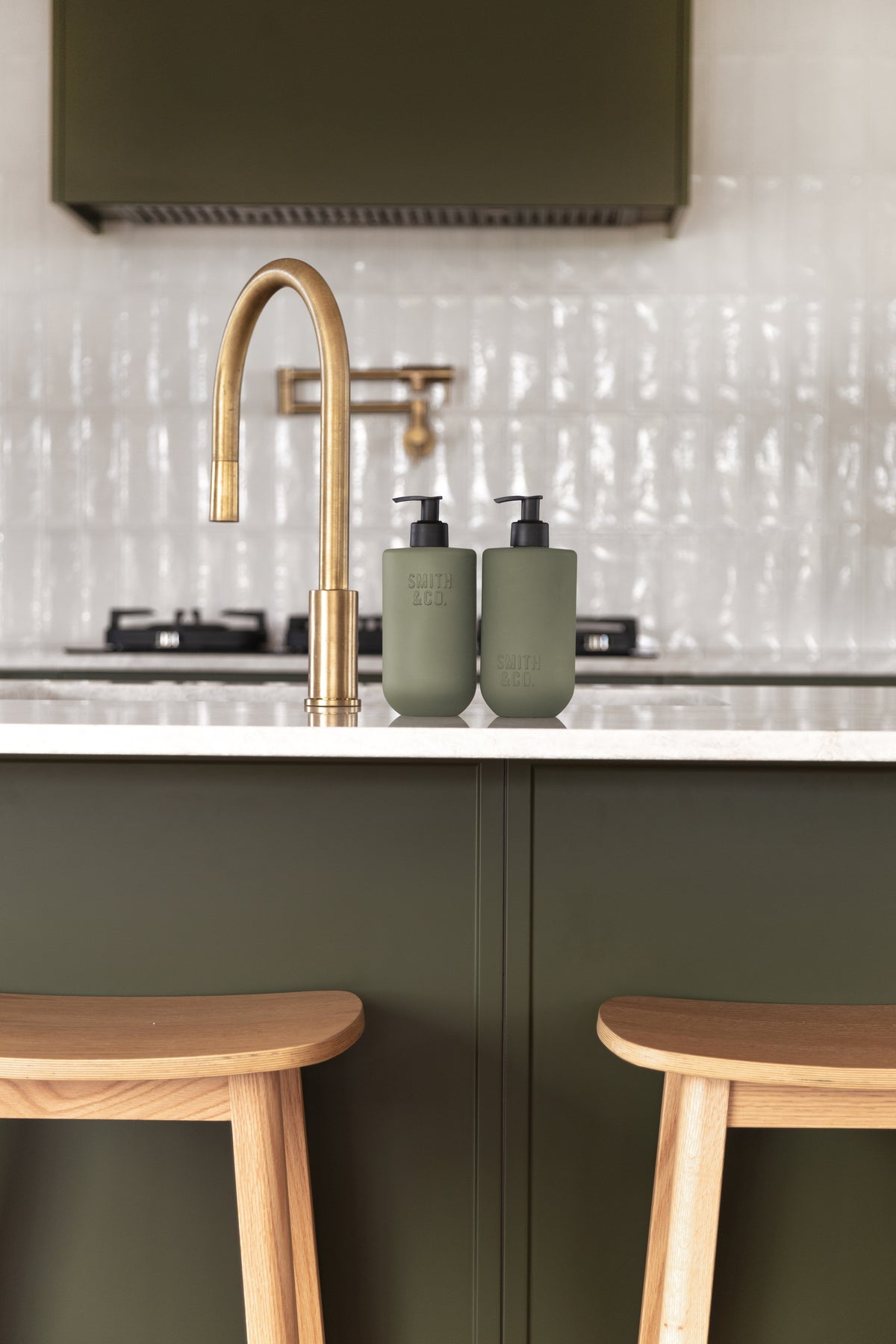 Sage green Smith & Co. bottles on a kitchen bench above timber bar stools