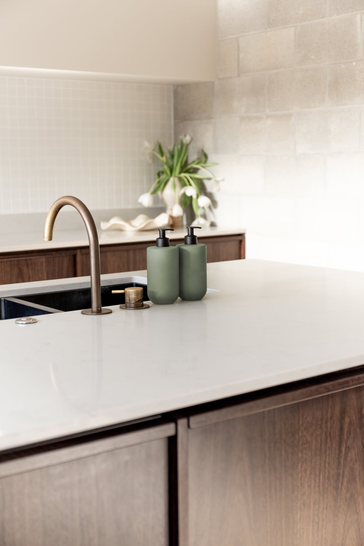 Kitchen benchtop with a brass tap, a plant and Smith & Co. bottles