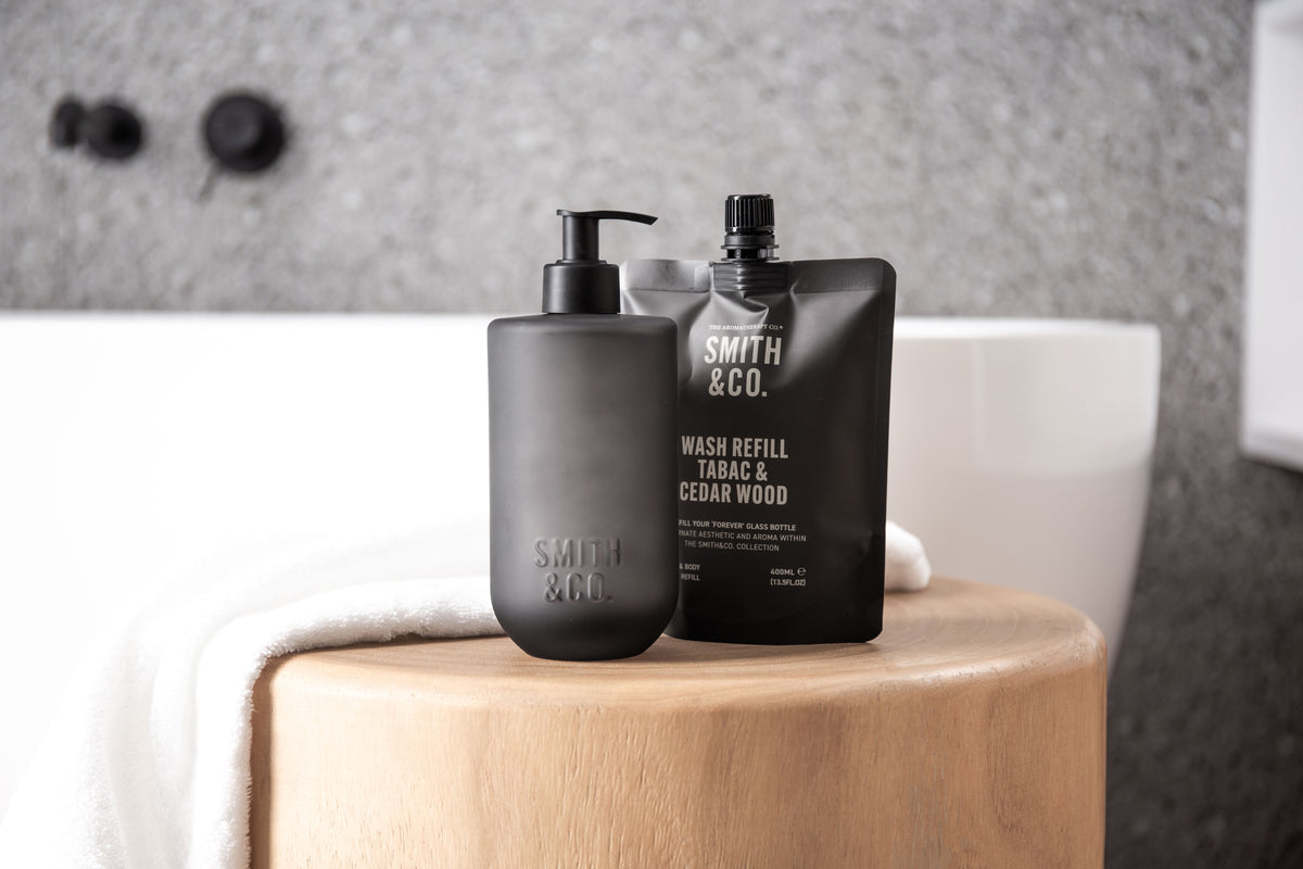 Smith & Co. bottle and refill pouch on a timber stool beside a white bath