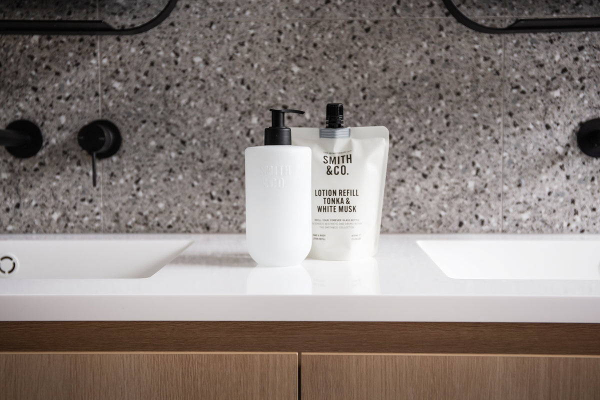 Smith & Co. wash bottle and refill pouch between twin basins with black tapware and terrazzo