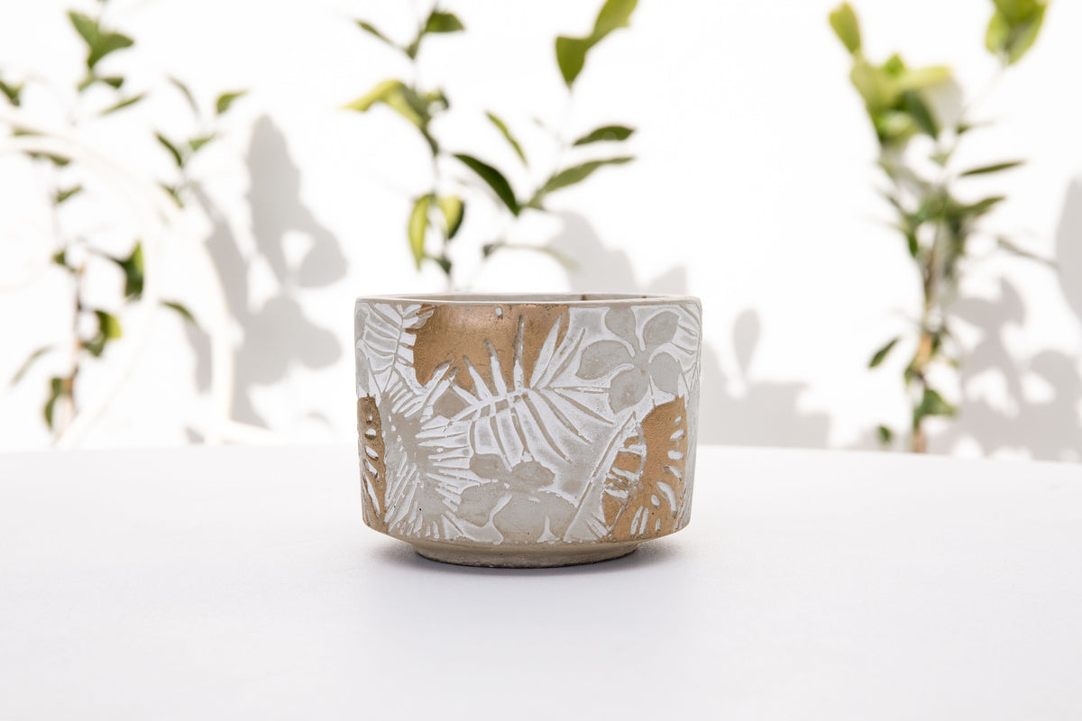 Landscape shot of the unlit candle on a white table with leafy branch shadows behind