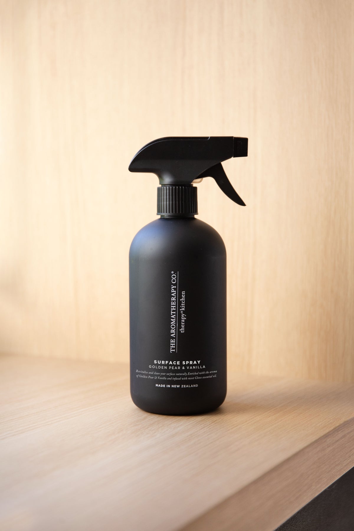 Black surface spray bottle standing on a pale timber ledge