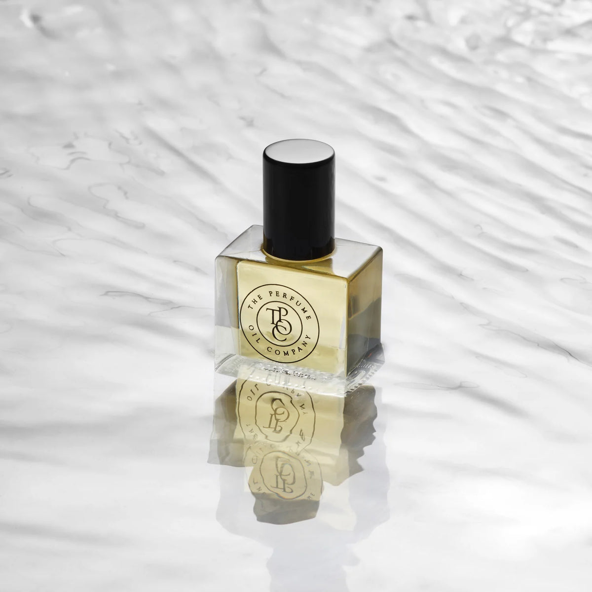 Perfume oil bottle on a mirrored surface against rippled water