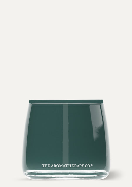 Therapy Garden candle in glossy deep green glass on a pale background
