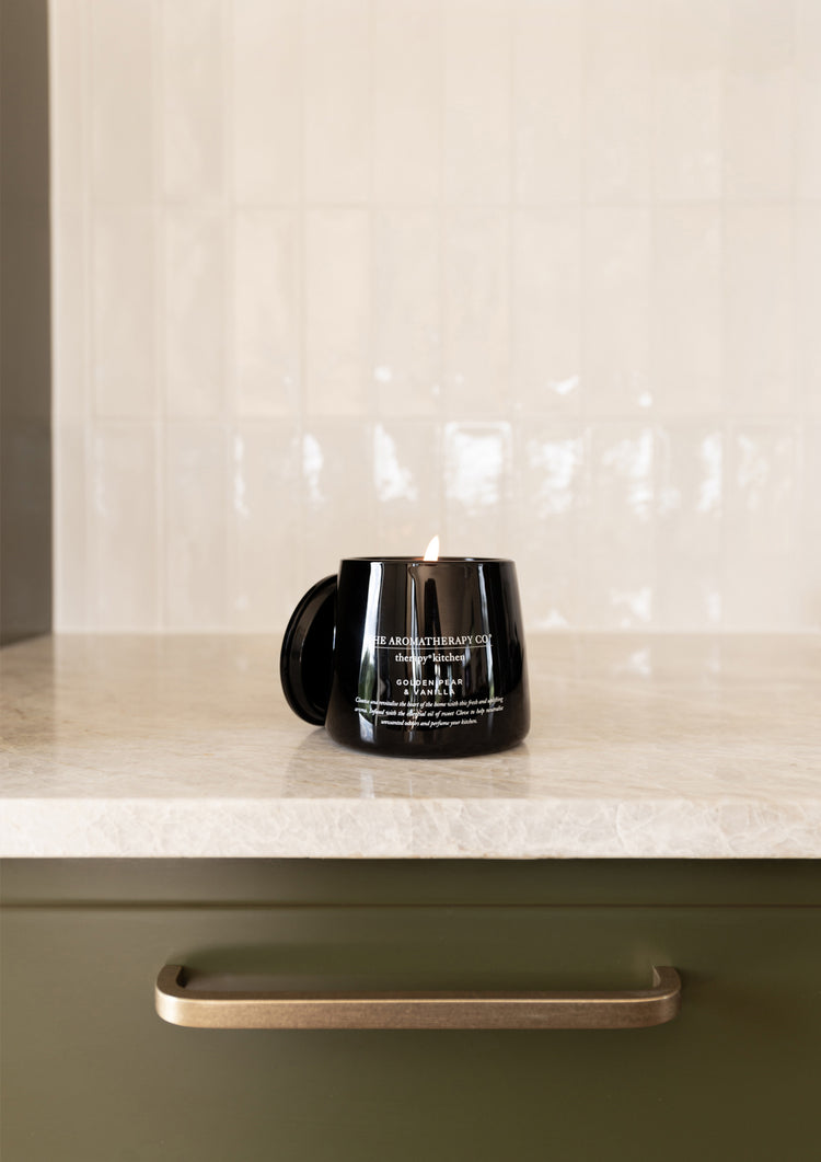 Black Therapy Kitchen candle on a benchtop against a white tiled splashback