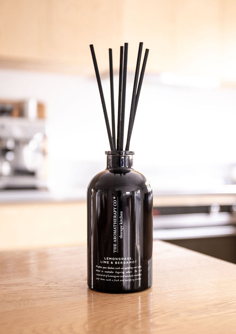 Therapy Kitchen citrus reed diffuser on a timber kitchen bench with a softly blurred kitchen behind