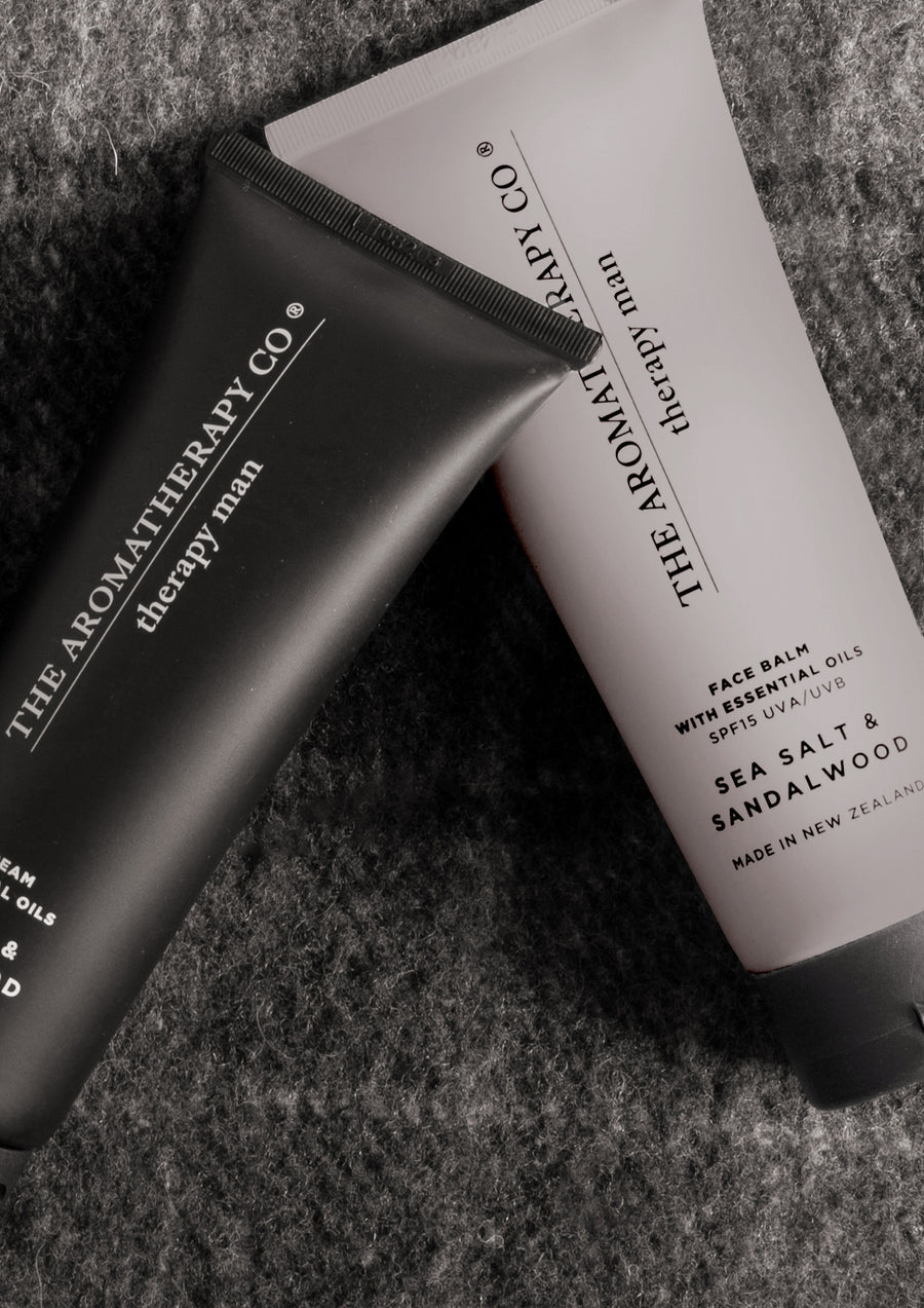 Black shave cream tube and grey Therapy Man tube crossed on a charcoal wool throw