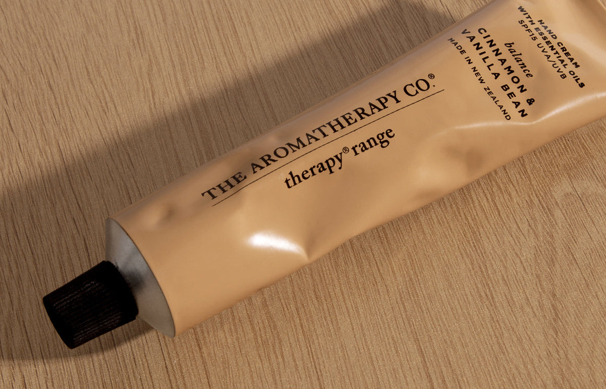 Caramel hand cream tube lying diagonally on light oak, landscape view