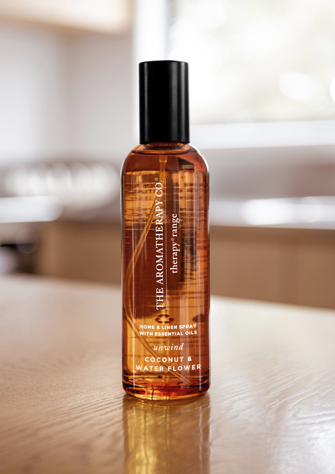 Coconut & Water Flower room spray on a timber table with a bright kitchen blurred behind