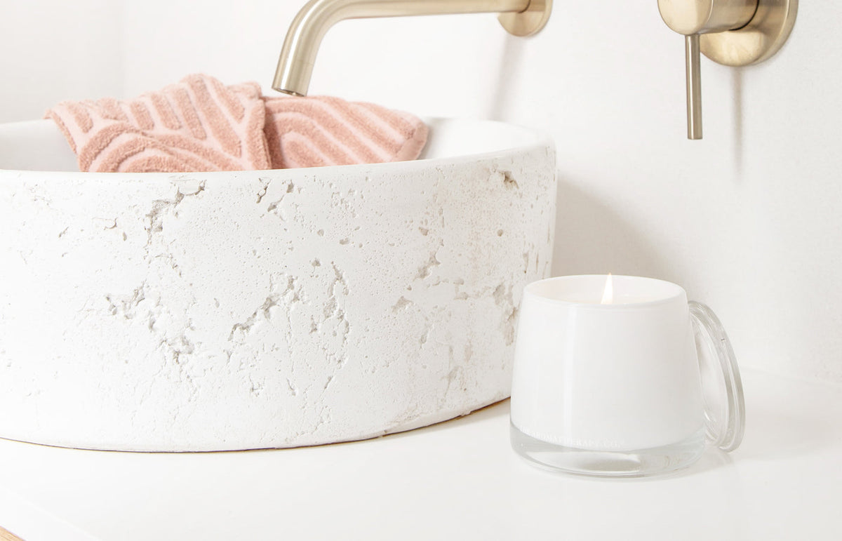 Therapy candle on a stone vanity beside a speckled basin