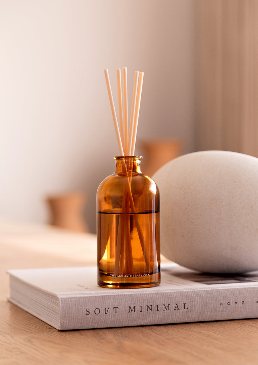 Close view of the Therapy diffuser on a book beside a smooth pale stone