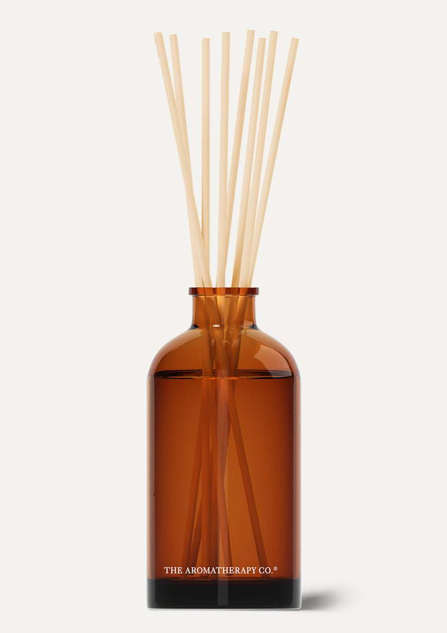 Amber Therapy reed diffuser with natural reeds on a pale background
