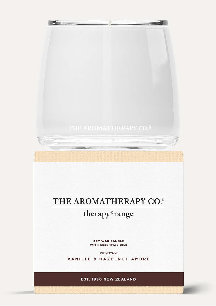 Therapy Embrace Vanille & Hazelnut Ambre candle stacked on its white and brown box