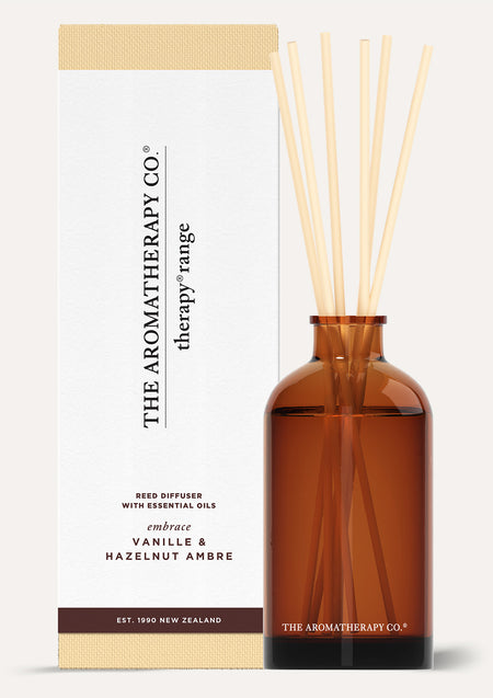 Therapy Embrace Vanille & Hazelnut Ambre reed diffuser in amber glass beside its white box