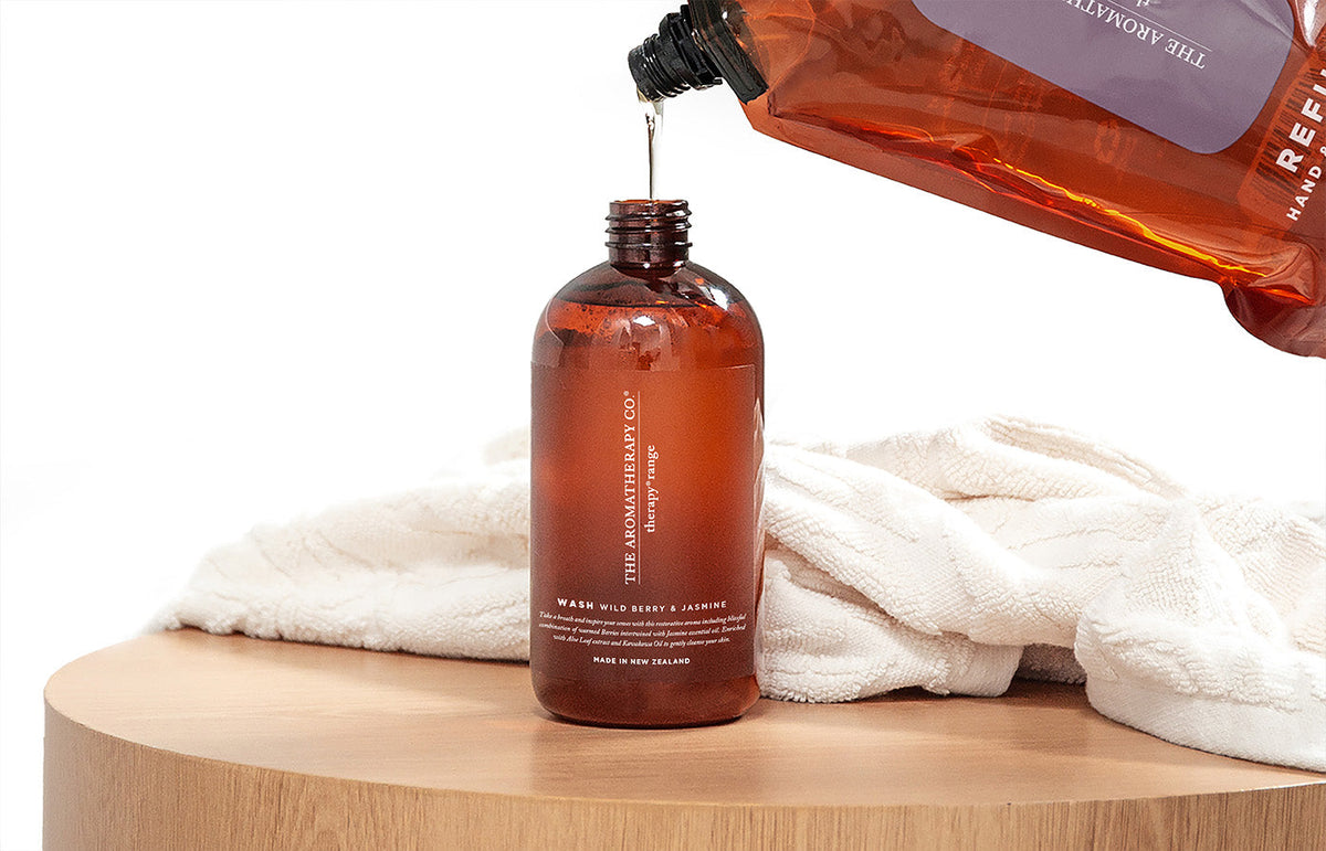 Amber wash being poured into a bottle set on folded white towels on a round timber tray